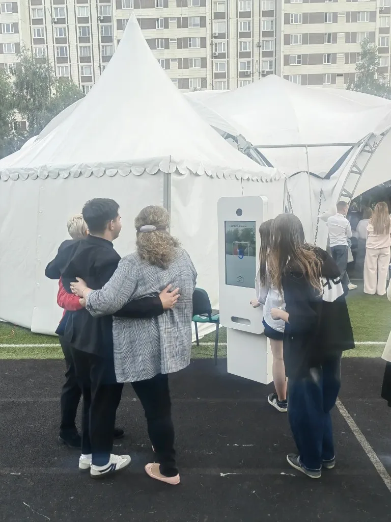 Гости фотографируются у фотокиоска на открытом мероприятии